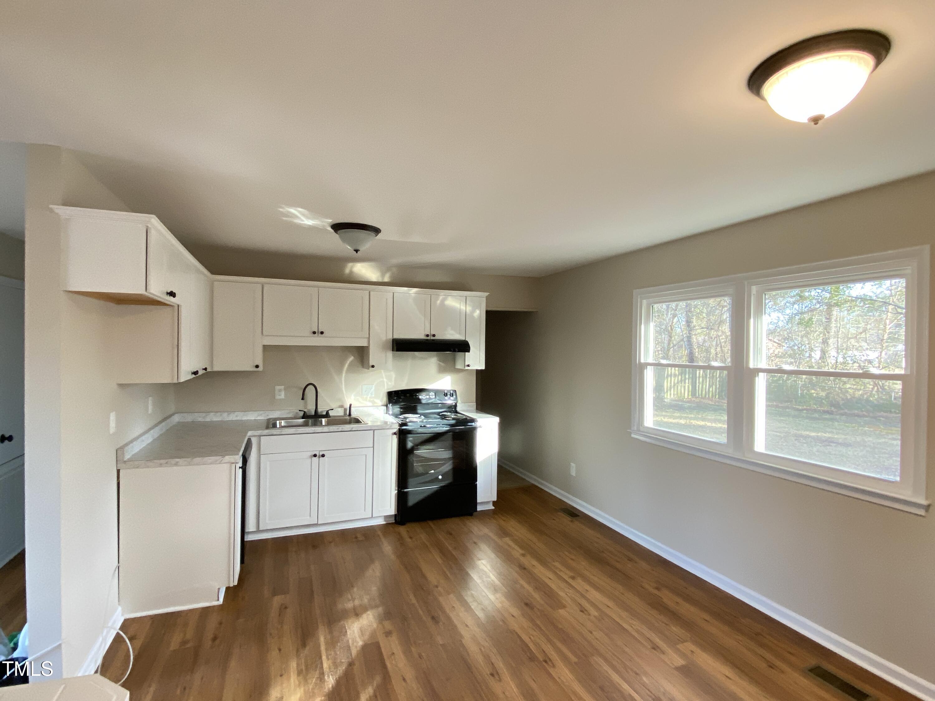 110 Sycamore Street Dunn, NC 28334 - Photo 6 of 28 a kitchen with stainless steel appliances granite countertop a stove a sink and white cabinets with wooden floor