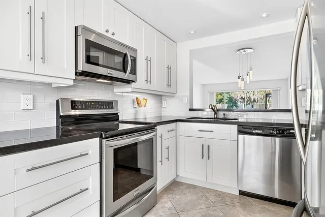 a kitchen with white cabinets stainless steel appliances and sink