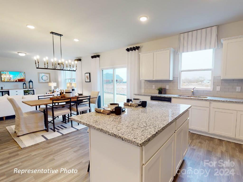 1207 Dan River Southwest, Unit 159 Concord, NC 28027 - Photo 5 of 13 a open kitchen with granite countertop a table chairs sink and cabinets