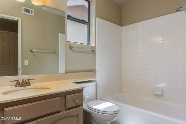 a bathroom with a granite countertop sink a toilet and shower