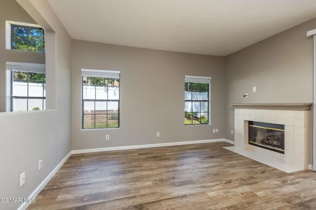 an empty room with windows and fireplace