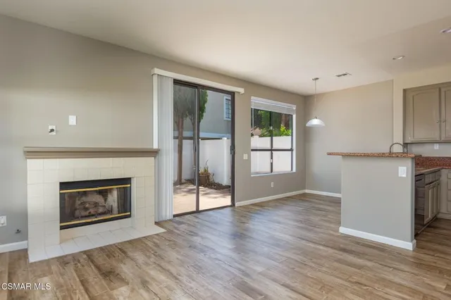 a view of a livingroom with a fireplace a ceiling fan and windows