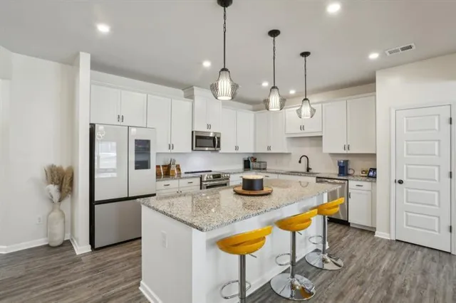 a kitchen with stainless steel appliances granite countertop a sink a stove a refrigerator and island with wooden floor