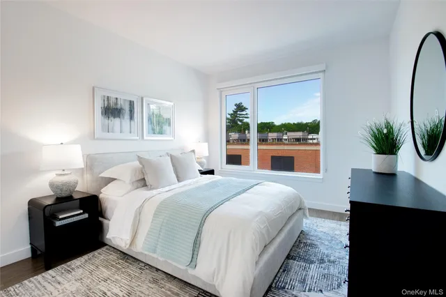 a bedroom with a large bed and a potted plant on the dresser