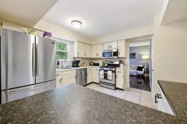 a kitchen with granite countertop a refrigerator stove top oven and sink