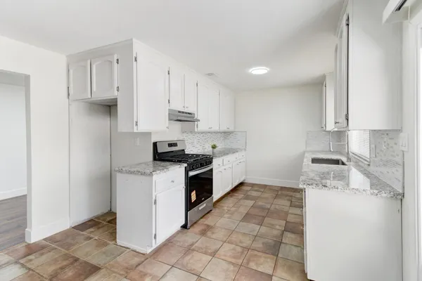a kitchen with a sink a stove top oven and white stainless steel appliances
