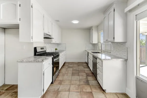 a kitchen with stainless steel appliances granite countertop a stove a sink and a microwave