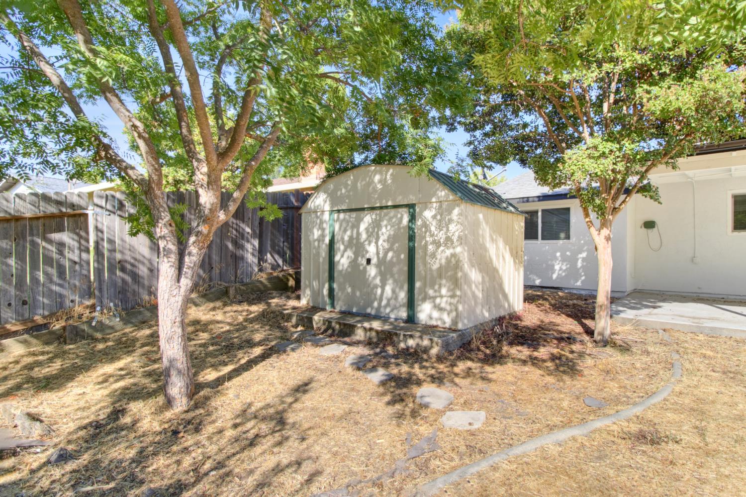 124 Fargo Way Folsom, CA 95630 - Photo 53 of 60 a backyard of a house with large trees and a wooden fence
