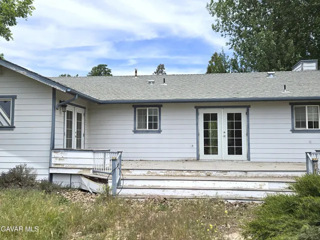 a view of a house with a small yard and wooden fence
