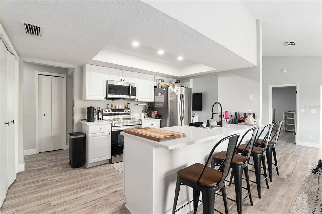 10234 Bedford Road Spring Hill, FL 34608 - Photo 12 of 31 a kitchen with stainless steel appliances kitchen island granite countertop a table chairs refrigerator and microwave