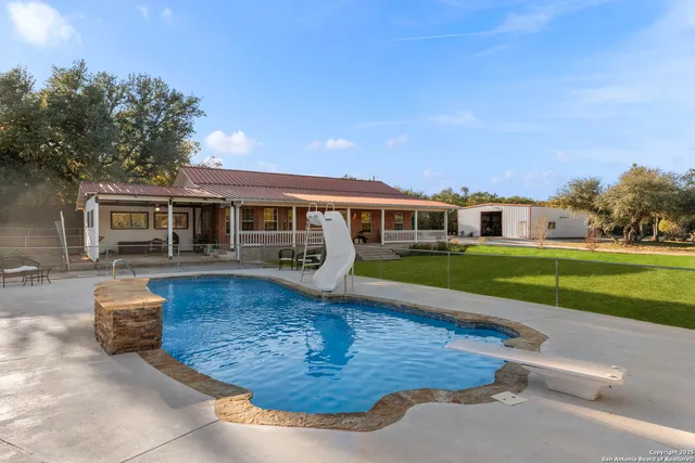 a view of house with swimming pool and yard
