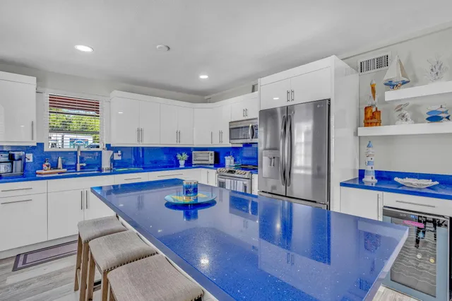 a kitchen with stainless steel appliances granite countertop a refrigerator a stove and white cabinets with wooden floor