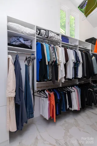a view of walk in closet with clothes and shoes