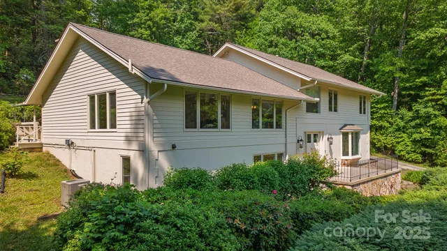 a view of a white house next to a yard with large trees