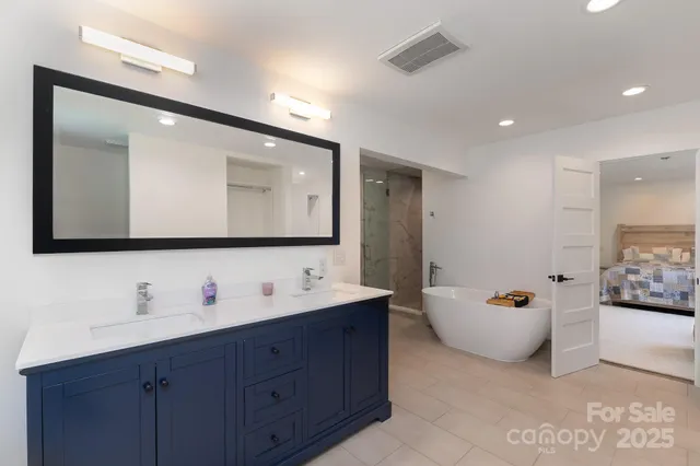 a bathroom with a double vanity sink mirror and bathtub