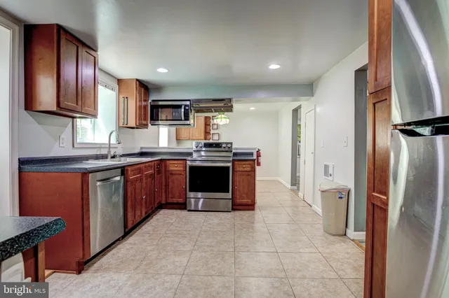 a large kitchen with stainless steel appliances granite countertop a refrigerator and a sink