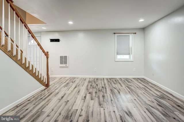a view of an empty room with wooden floor and stairs