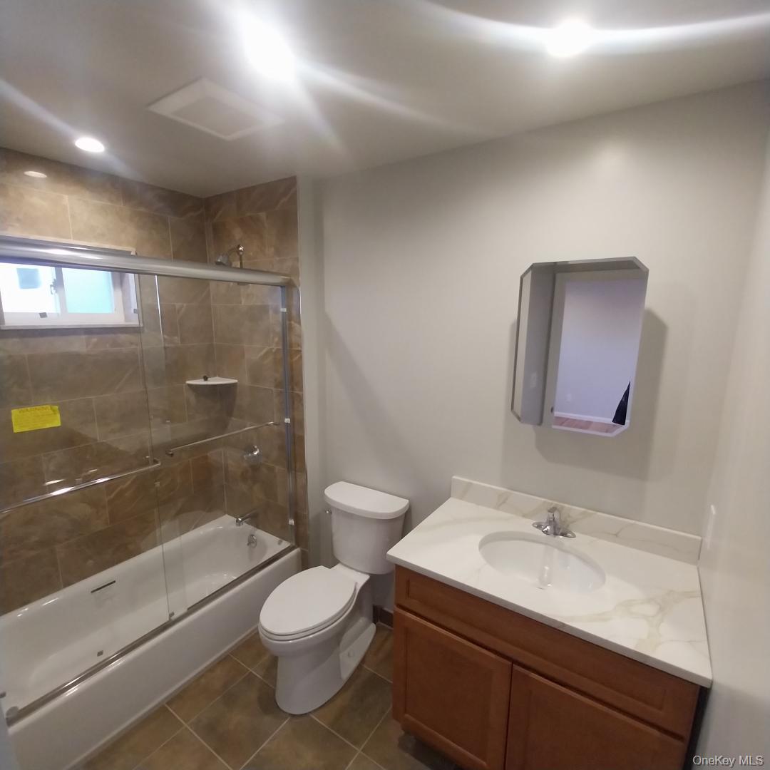 343 Jackson Street, Unit 5 Hempstead, NY 11550 - Photo 11 of 16 Bathroom with enclosed tub / shower combo, vanity, and dark tile patterned flooring