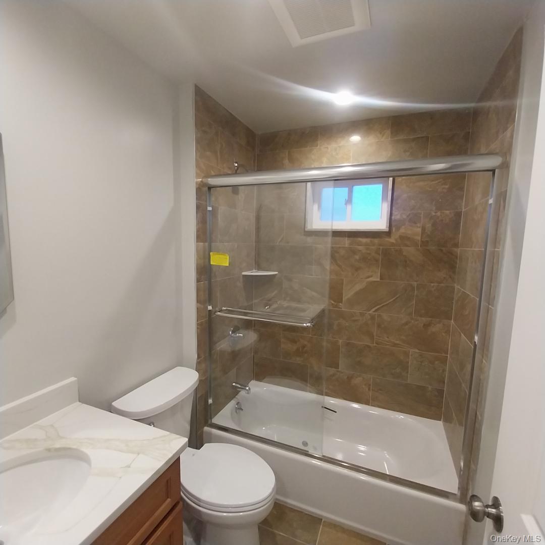 343 Jackson Street, Unit 5 Hempstead, NY 11550 - Photo 12 of 16 Bathroom with bath / shower combo with glass door, vanity, and tile patterned flooring