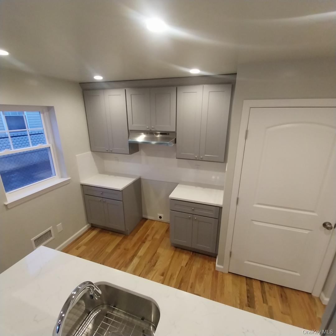 343 Jackson Street, Unit 5 Hempstead, NY 11550 - Photo 2 of 16 Kitchen with gray cabinetry, light wood-style floors, under cabinet range hood, recessed lighting, and light stone countertops