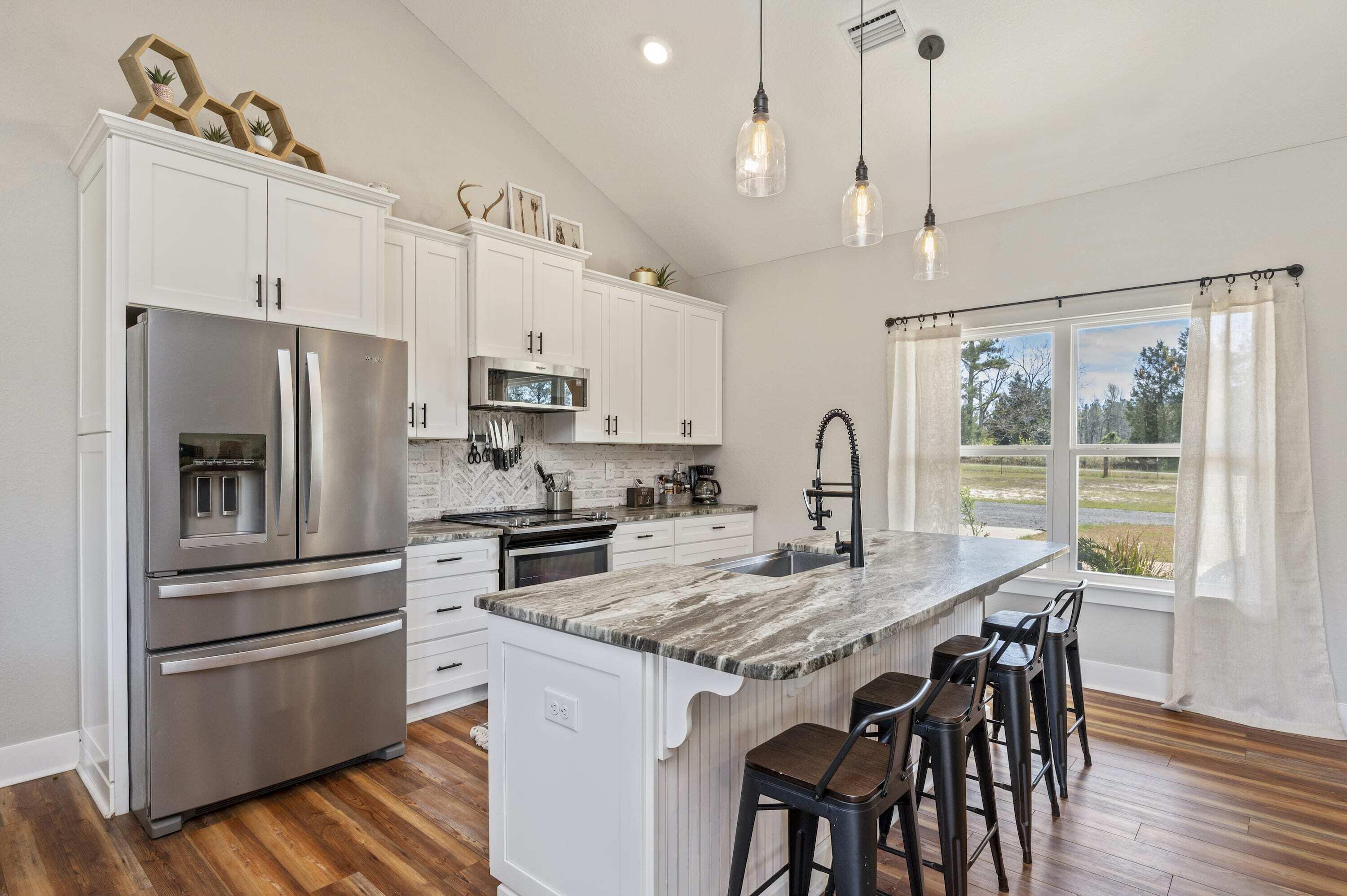 8151 Tommy Steele Road Baker, FL 32531 - Photo 21 of 36 a kitchen with granite countertop a table chairs stainless steel appliances and wooden floor