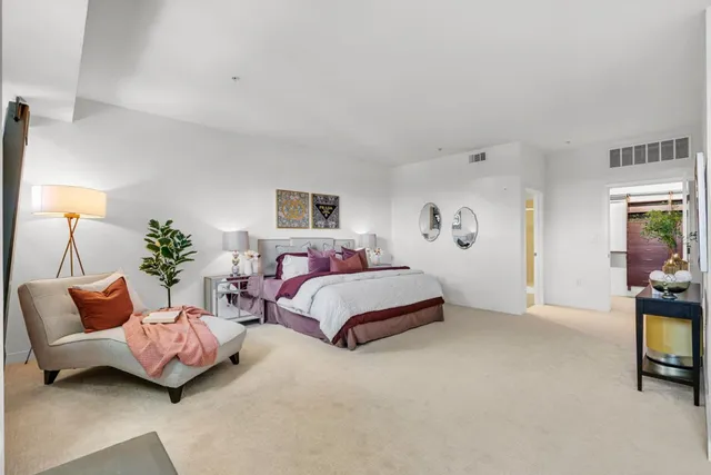 a spacious bedroom with a bed a couch and a potted plant