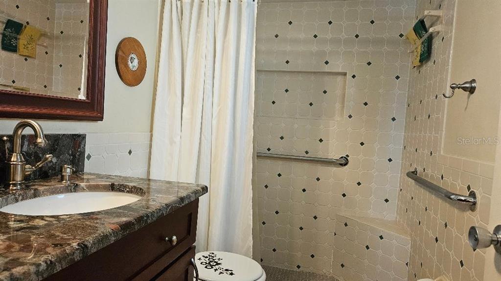 4600 98th Way North, Unit 210 St. Petersburg, FL 33708 - Photo 16 of 33 a bathroom with a granite countertop sink and a mirror