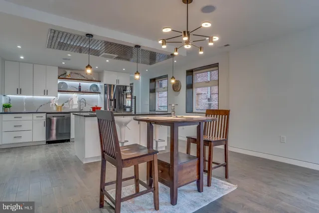 a dining room with kitchen island stainless steel appliances furniture a chandelier and kitchen view