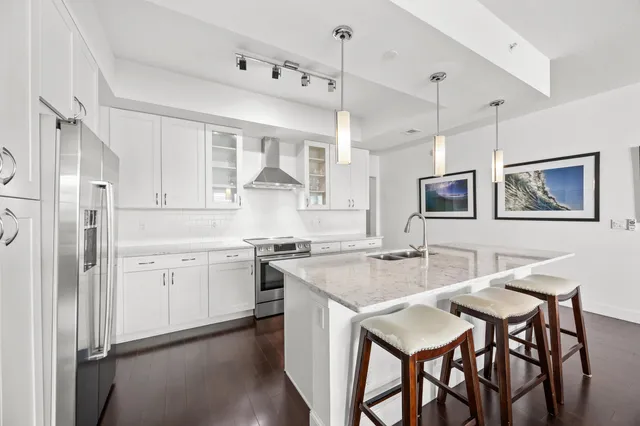 a kitchen with stainless steel appliances granite countertop a stove a sink refrigerator and white cabinets