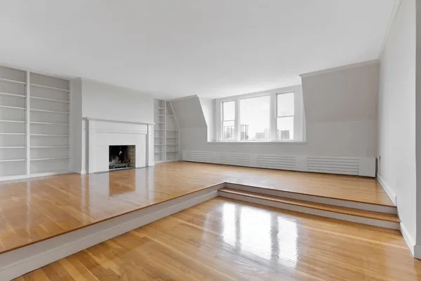 a view of empty room with wooden floor and fireplace