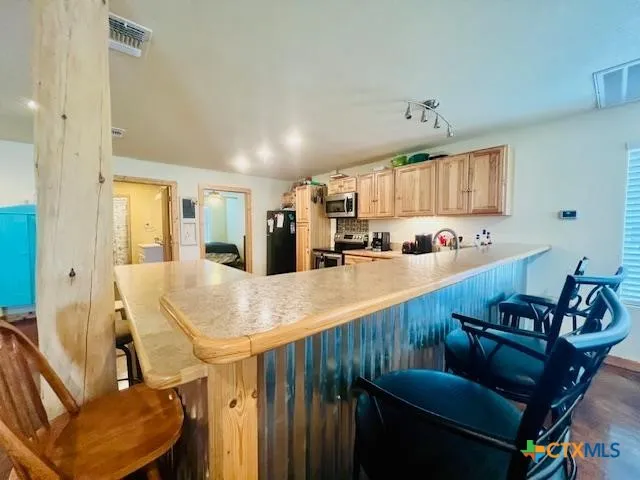 a kitchen with stainless steel appliances kitchen island granite countertop a refrigerator a stove and a sink with wooden floor