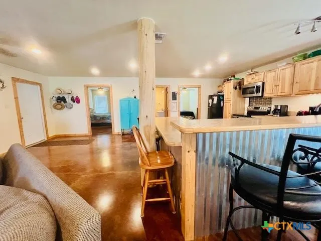 a room with stainless steel appliances kitchen island granite countertop furniture and a refrigerator