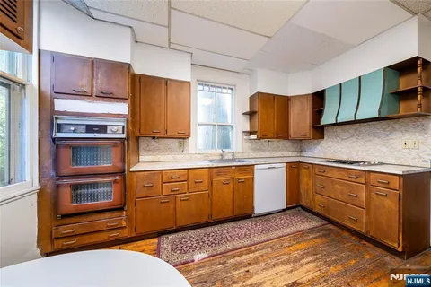 a kitchen with stainless steel appliances granite countertop a sink dishwasher stove and refrigerator with wooden cabinets