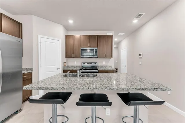 a kitchen that has a sink a stove top oven a refrigerator and a island with wooden floor