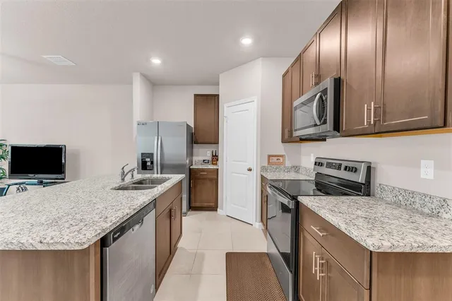 a kitchen with kitchen island granite countertop a sink stove and refrigerator
