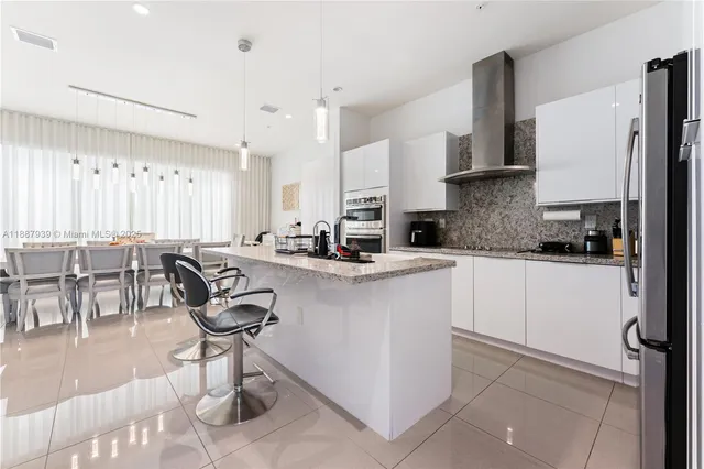 a kitchen with stainless steel appliances granite countertop a sink a stove a refrigerator cabinets and chairs