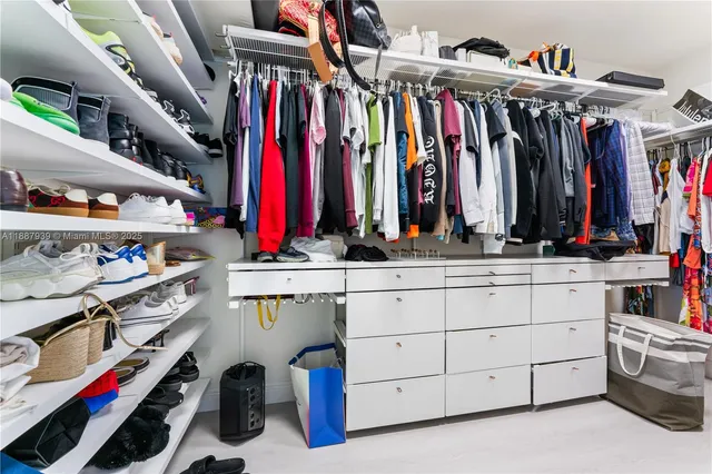 a view of walk in closet with clothes and shoes