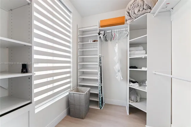 a view of walk in closet with clothes and shoes