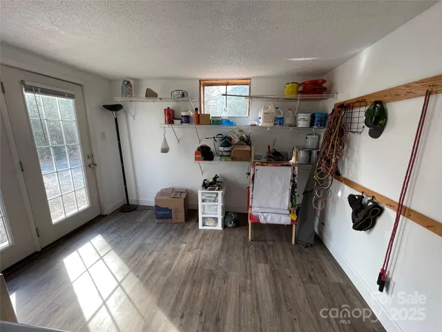 a view of a refrigerator in kitchen and an empty room with wooden floor and windows