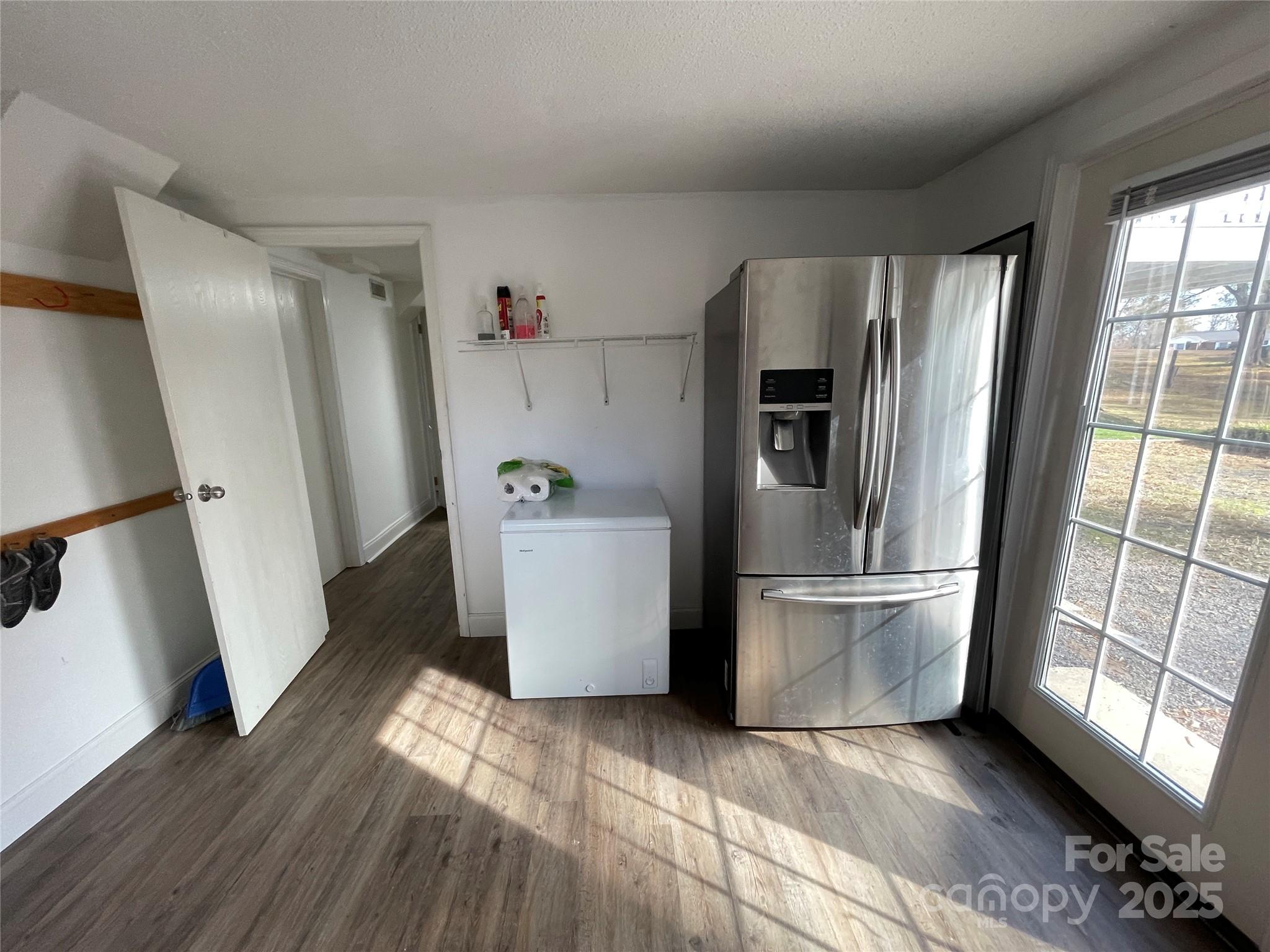 613 Gurley Street Albemarle, NC 28001 - Photo 32 of 43 a view of a refrigerator in kitchen and an empty room with wooden floor and windows