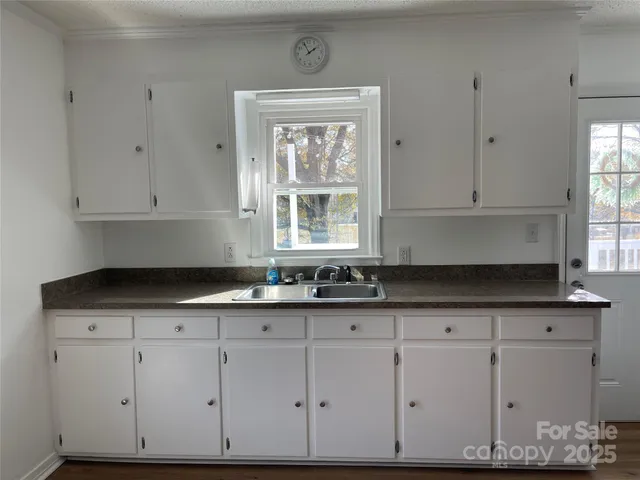 a kitchen with granite countertop white cabinets and a sink