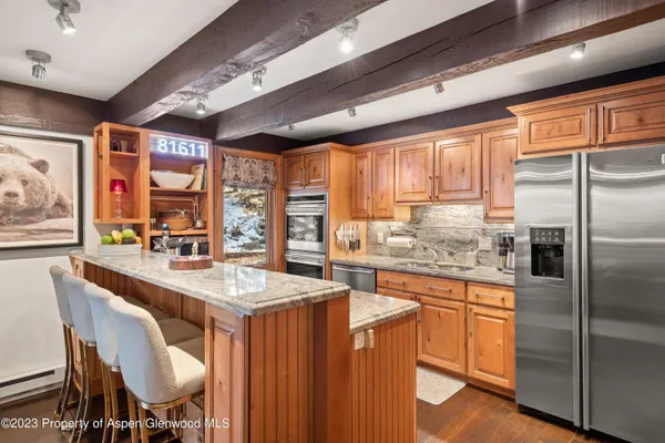 a kitchen with stainless steel appliances granite countertop a stove a refrigerator a sink dishwasher with a dining table and chairs