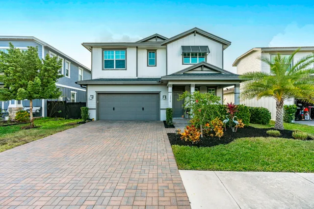 a front view of a house with a yard and potted plants