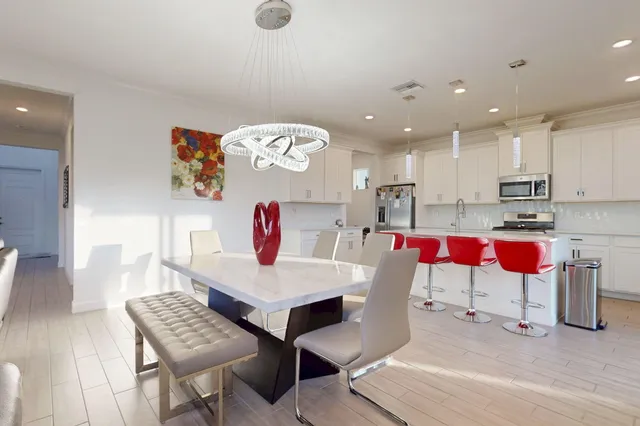 a kitchen with stainless steel appliances granite countertop a kitchen island hardwood floor sink stove dining table and chairs