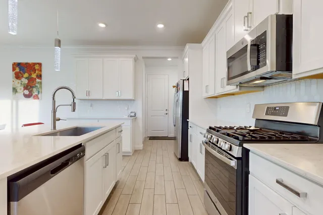 a kitchen with kitchen island granite countertop a sink and white cabinets with wooden floor