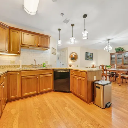 a kitchen with stainless steel appliances granite countertop a sink a stove and a wooden floors