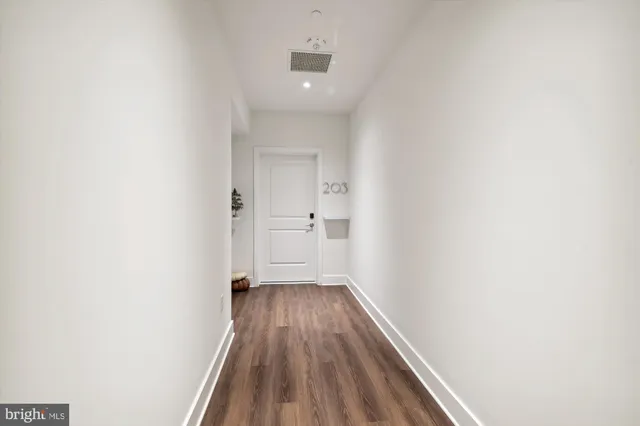 a view of a hallway with wooden floor and a bathroom