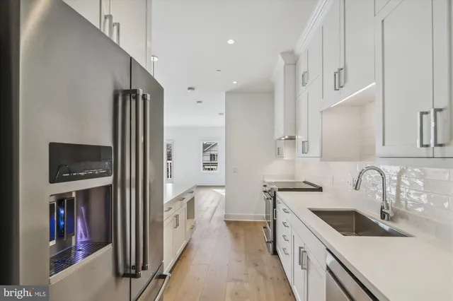 a large white kitchen with kitchen island a sink a stove and white cabinets