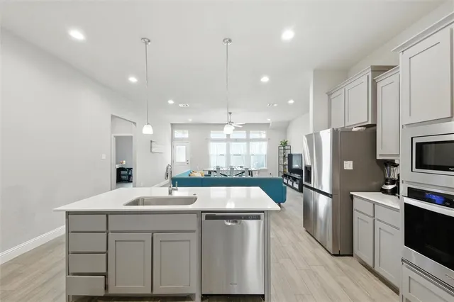a kitchen with a sink a center island stainless steel appliances and windows