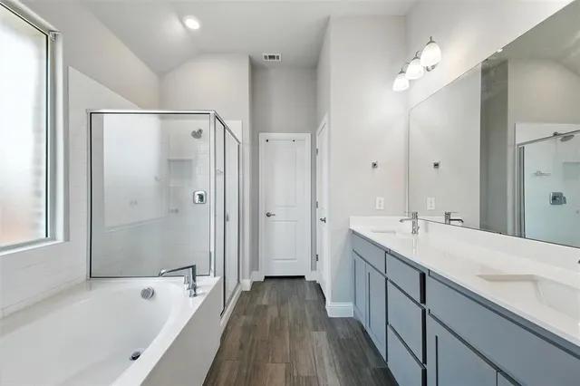 a spacious bathroom with a tub sink shower and mirror